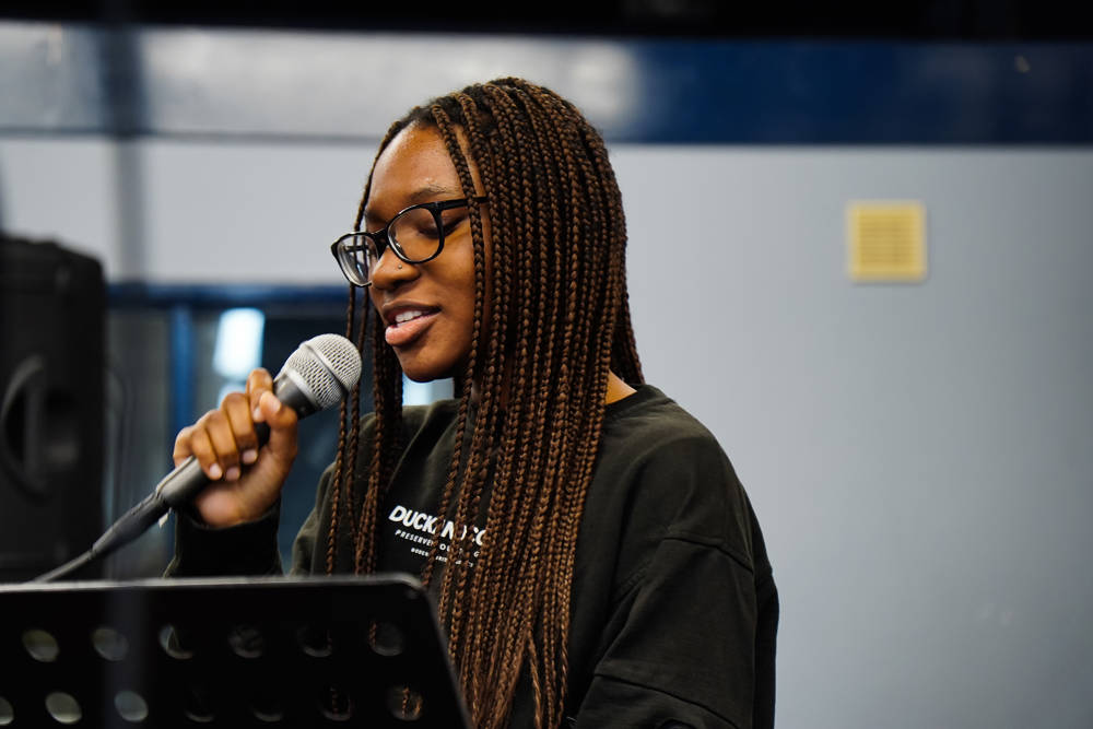 Female music technology student holding microphone in studio.