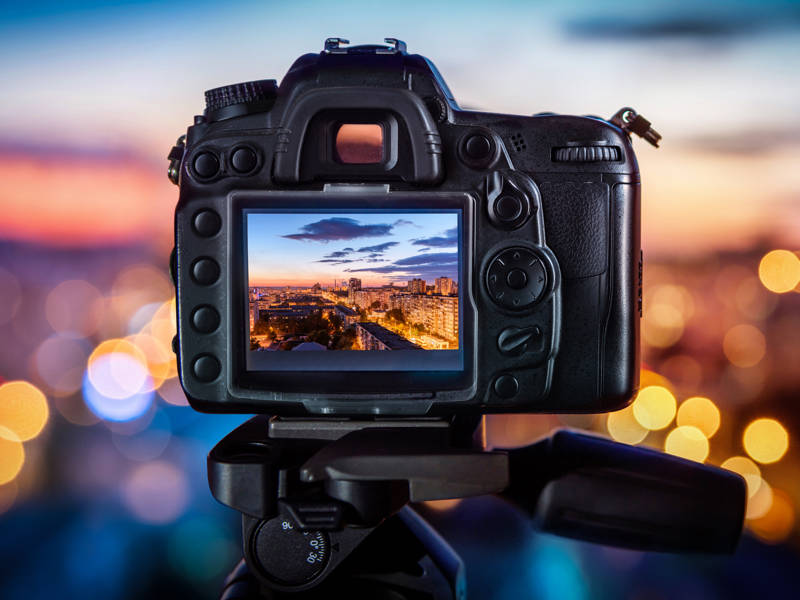 An SLR camera on a background of blurry city lights.