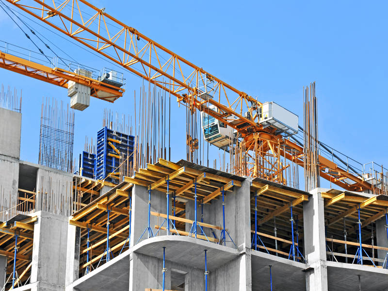 Crane and building construction site against blue sky