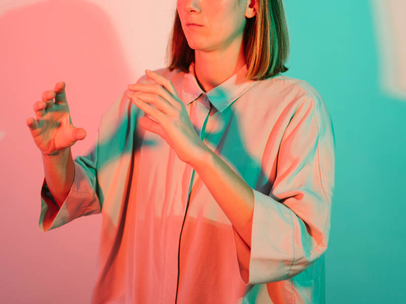 Young lady uses sign language gesture meaning communication with colourful background