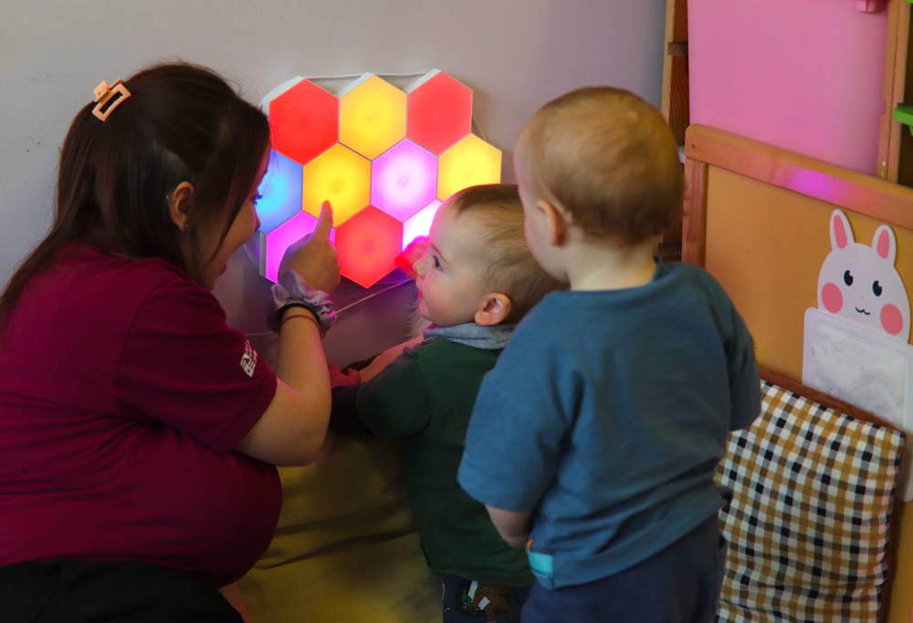 Babies in nursery playing with sensory lights.