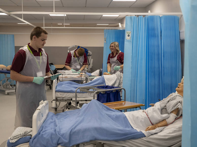 Students working with medical manikins in the Healthcare suite at City of Portsmouth College 