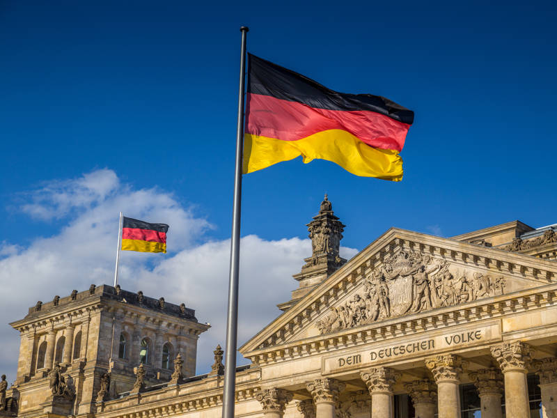 German flags waving in the wind at famous Reichstag building in Berlin on a sunny day with blue skys