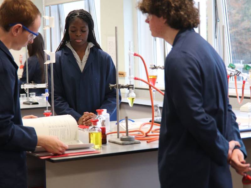 Students in lab coats in science lab at Sixth Form Campus.