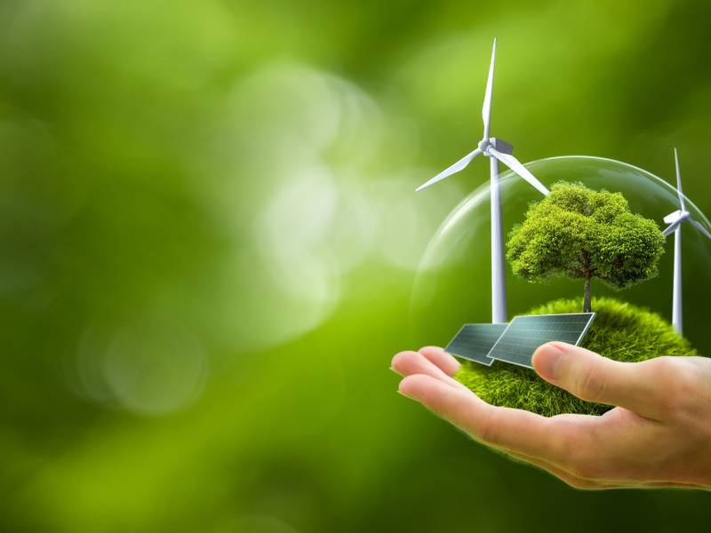 Hand holding a globe containing green energy.