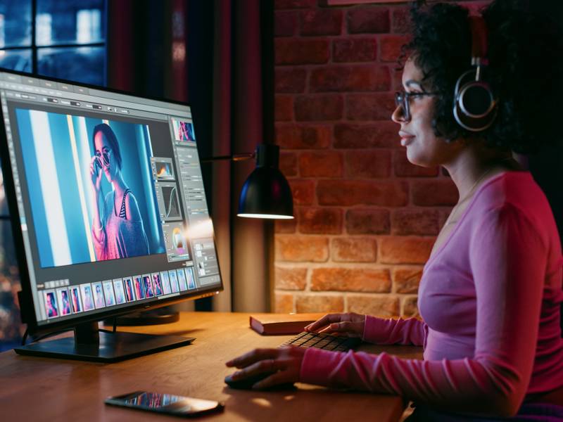 Young Creative in Headphones Using Computer in Stylish Loft Apartment in the Evening.