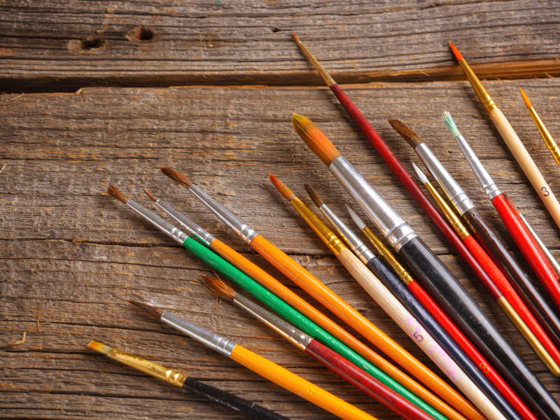 Artist paint brushes on wooden table background.