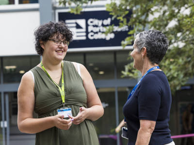 A staff member and student interacting outside City of Portsmouth College