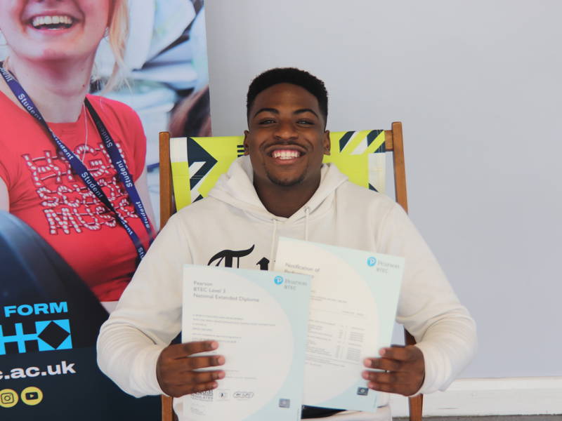 Smiling students holds up results certificates at results day event.