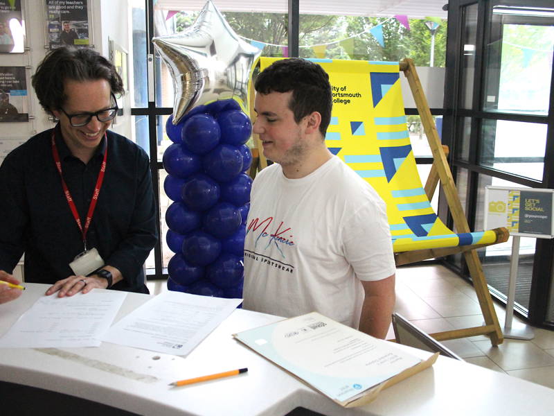 Student smiling with staff member during results day event.
