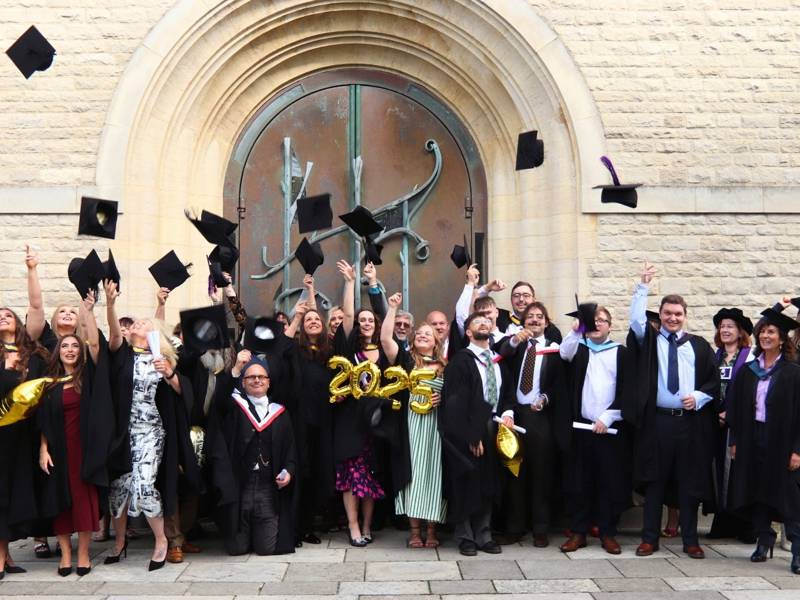 City of Portsmouth College's 2025 adult learner graduates throw their hats into the air outside Portsmouth Cathedral