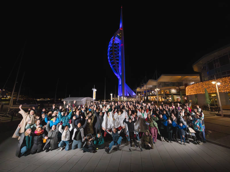 A group of people cheering in front of Portsmouth's Spinnaker Tower