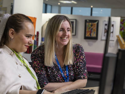 A  COPC staff member helping a student on a computer 