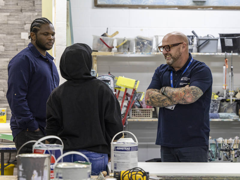 A painting and decorating lecturer talking to prospective students at City of Portsmouth College's Open Event