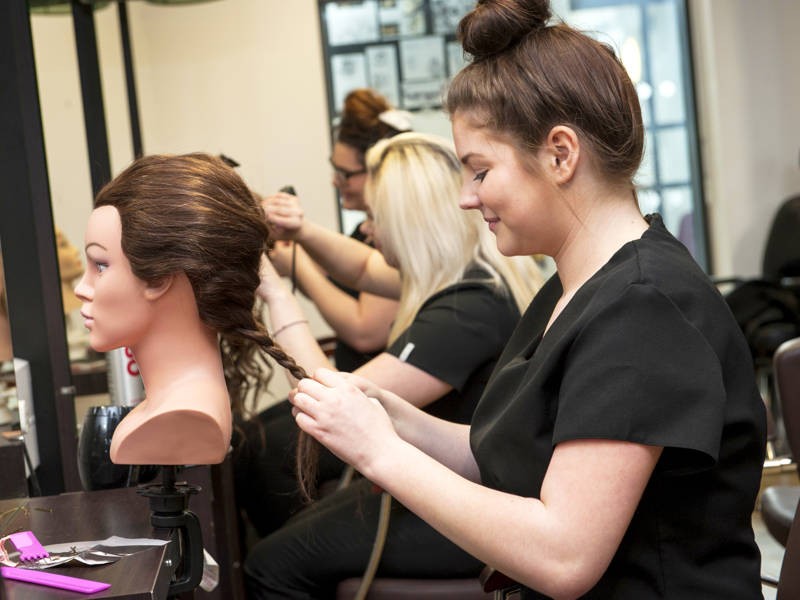 Hairdressing student works on head model in the Eden Salon at Highbury Campus